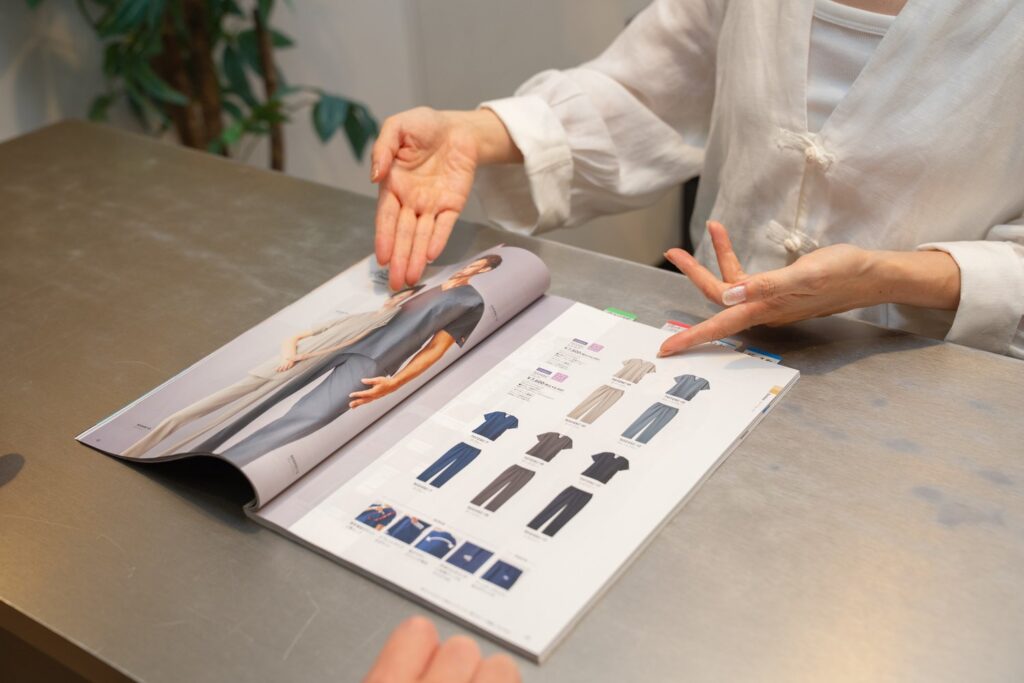 イメージ：カタログから、スタッフ用のウェアを案内している様子